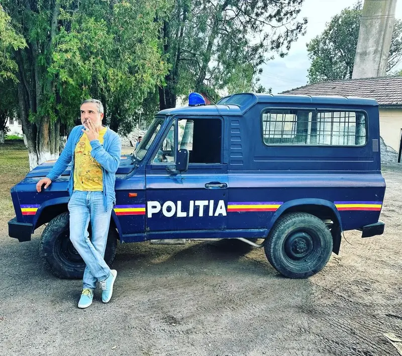Actor lângă o mașină de epocă a Poliției Române, recuzită de platou