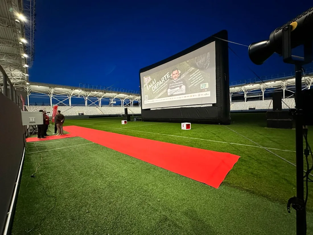 Covor roșu spre ecranul de cinema în aer liber montat pe stadion, în amurg
